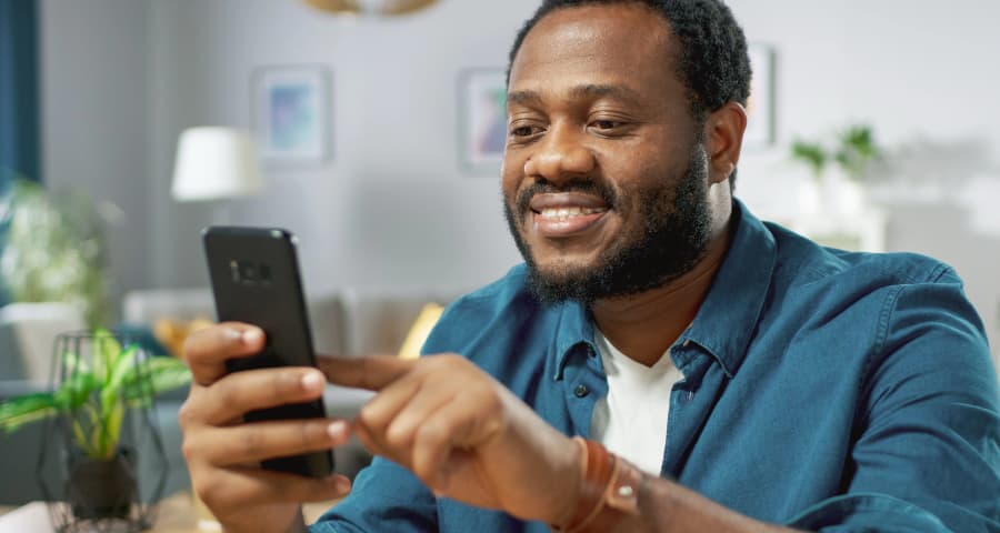 Man sitting down interacting with a home security app on his phone